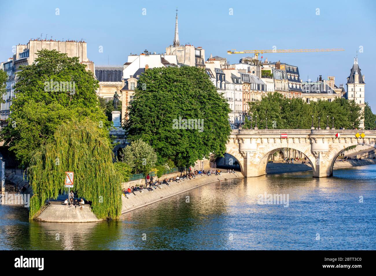 Paris, France - 14 mai 2020 : vue sur les personnes assises et ensoleignant sur les rives de la Seine, sur l'Ile de la Cité, près du Pont neuf et de la place d Banque D'Images