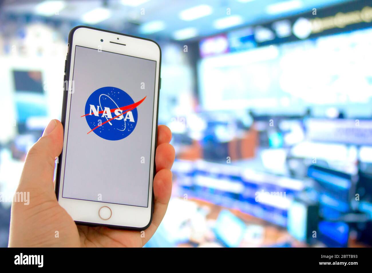 Kennedy Space Center, Floride, États-Unis. 27 mai 2020. Personne tenant un iPhone avec le logo de la NASA et un lancement de contrôle de mission hors foyer Banque D'Images