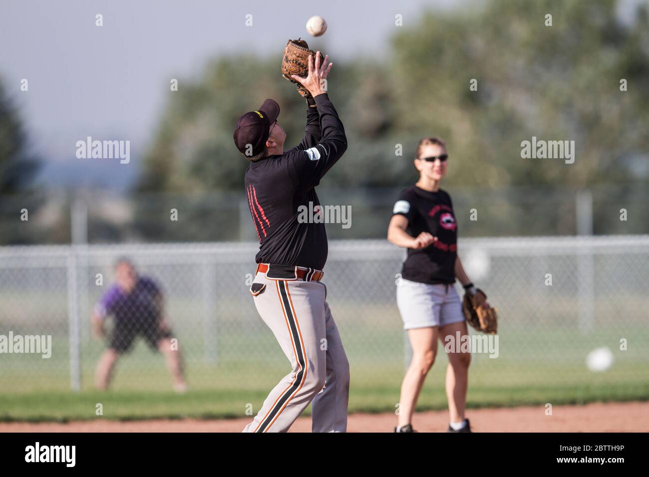 Jouer dans un jeu de softball à pas de Slo mixte, homme attrapant ballon de mouche, Banque D'Images