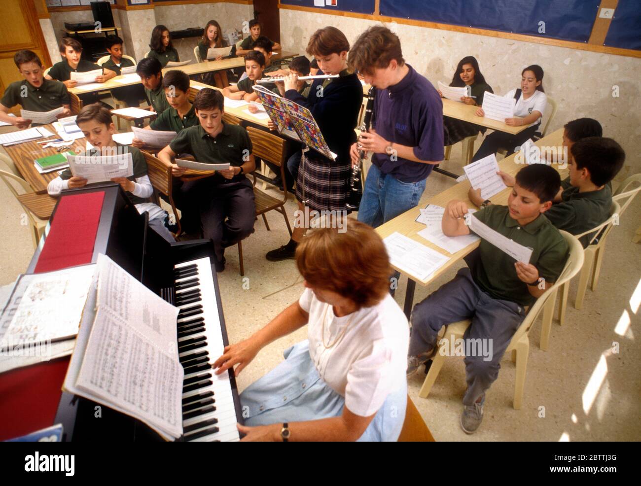 CLASSE DE MUSIQUE MULTICULTURELLE PARTITIONS DE MUSIQUE LECTURE ÉCOLE  GROUPE D'ENSEIGNANTS école junior 5-7 élèves élèves élèves élèves lisant de  la musique et chantant avec un professeur jouant du piano. Deux élèves