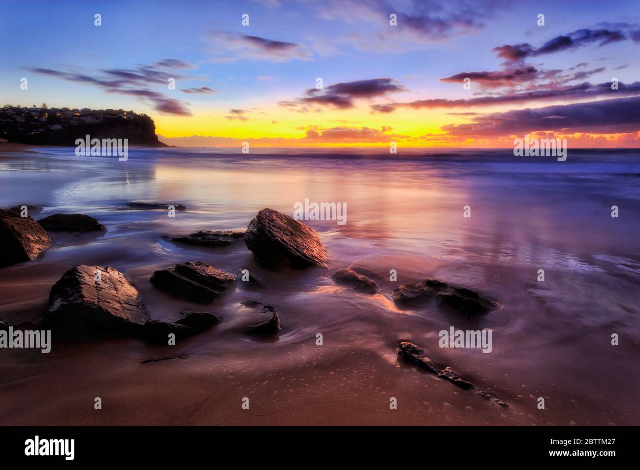 Rochers de grès ronds se tenant au lever du soleil sur la plage de sable de Bungan, sur les plages du nord de Sydney. Banque D'Images