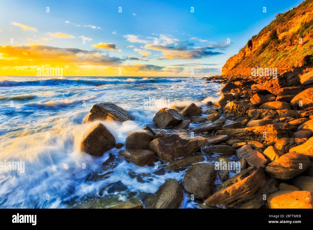 Rochers de grès sous promontoire à Bungan plage des plages du nord de Sydney dans la douce lumière du matin. Banque D'Images