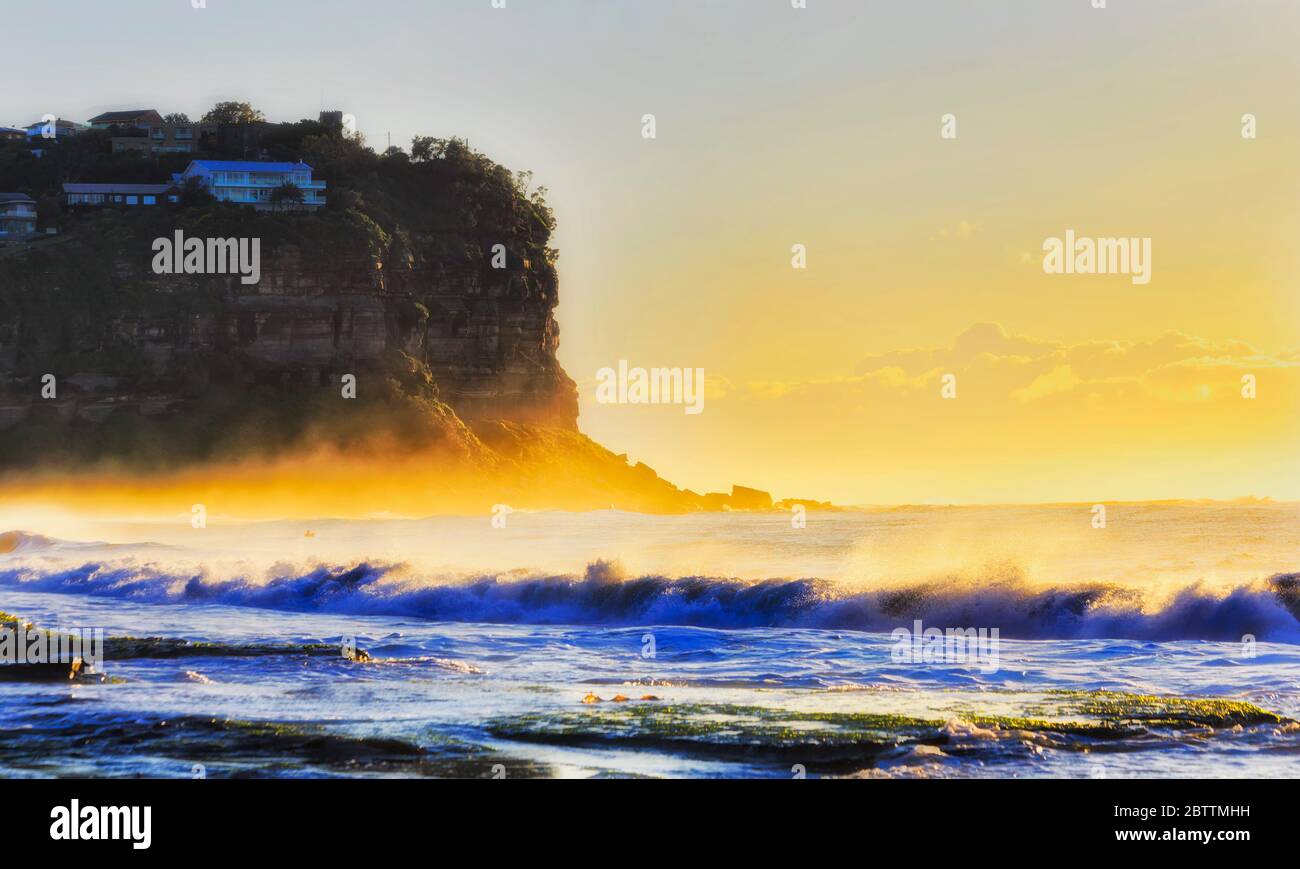 Immense promontoire en grès avec des maisons au sommet de la colline surplombant les plages du nord de Sydney au lever du soleil. Banque D'Images