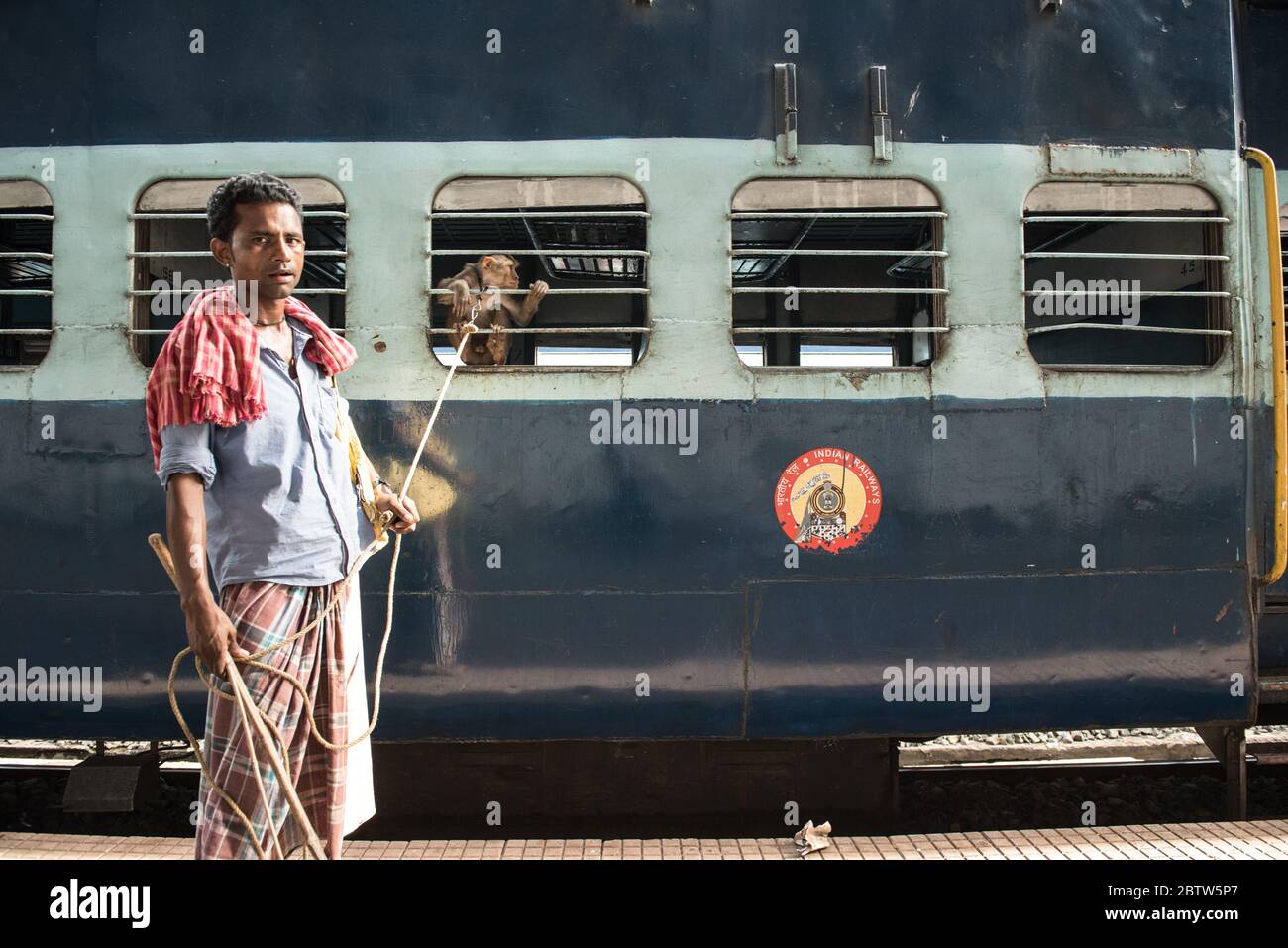 Homme avec Macaque Monkey à la gare de Howrah Junction, Kolkata, Inde. Banque D'Images