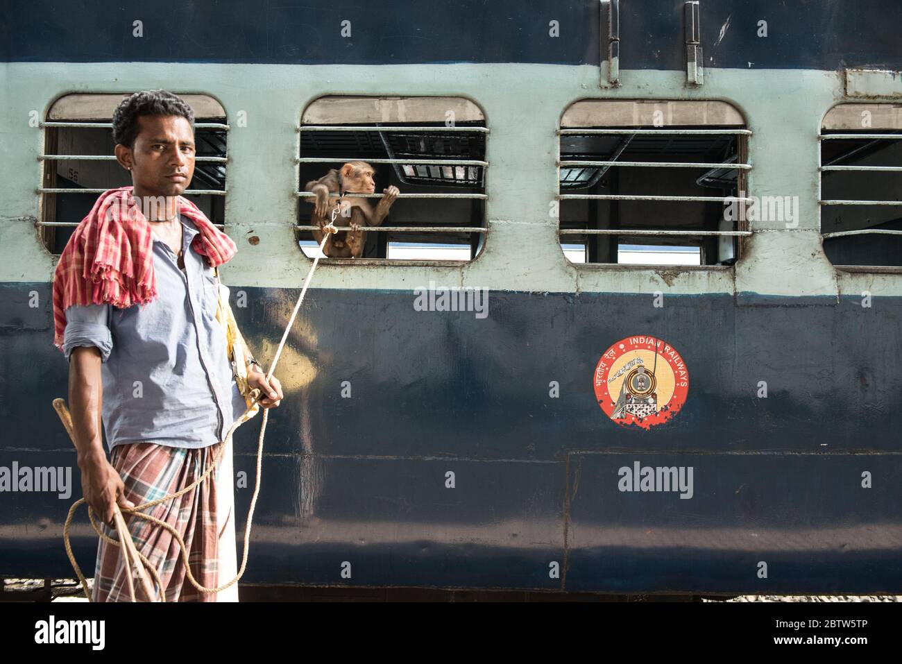 Homme avec Macaque Monkey à la gare de Howrah Junction, Kolkata, Inde. Banque D'Images