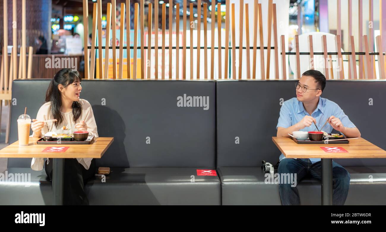 Homme et femme asiatiques mangeant de la nourriture sur table par une personne une table pour distancer social 6 feets concept de protection du coronavirus Covid-19 à la nourriture cour Banque D'Images