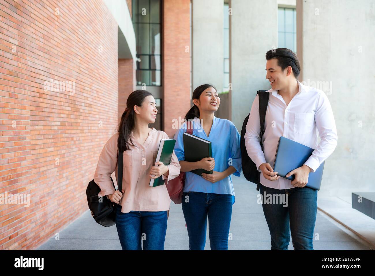 Asiatiques trois étudiants marchent et parlent ensemble dans le hall de l'université pendant une pause à l'université. Éducation, Apprentissage, Étudiant, Campus, Université, Banque D'Images