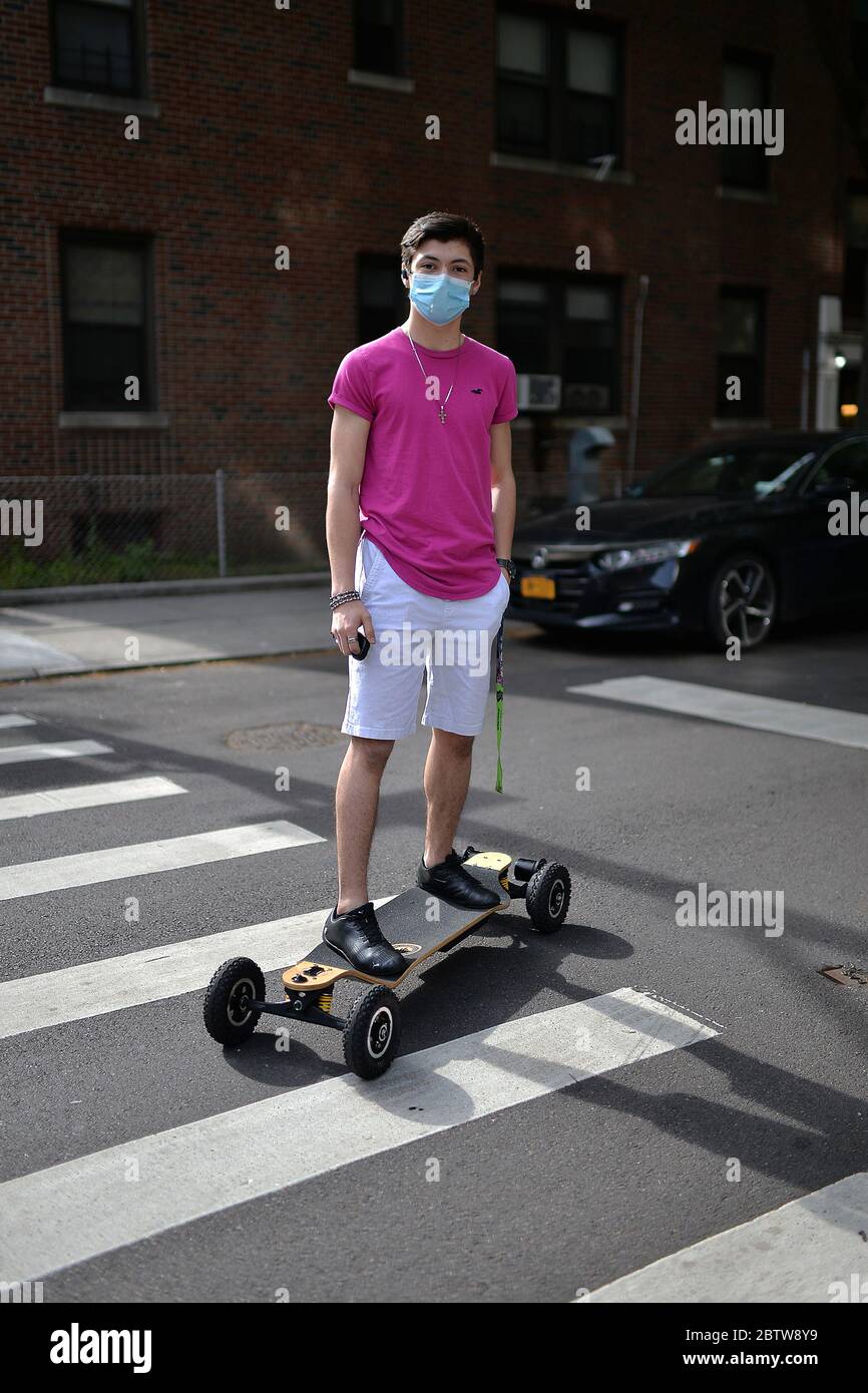 Un jeune homme portant un masque protecteur à l'époque de COVID-19, fait un skateboard électrique à travers Sunnyside, Queens, NY, le 27 mai 2020. (Anthony Behar/Sipa États-Unis) Banque D'Images Un jeune homme portant un masque protecteur à l'époque de COVID-19, fait un skateboard électrique à travers Sunnyside, Queens, NY, le 27 mai 2020. (Anthony Behar/Sipa États-Unis) Banque D'Images