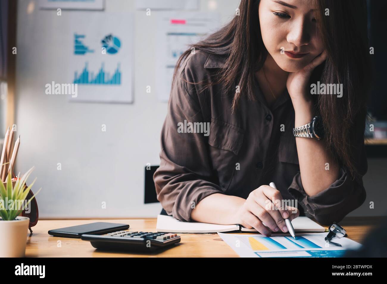 Femme d'affaires utilisant la calculatrice pour faire des finances mathématiques sur un bureau en bois dans le bureau Banque D'Images