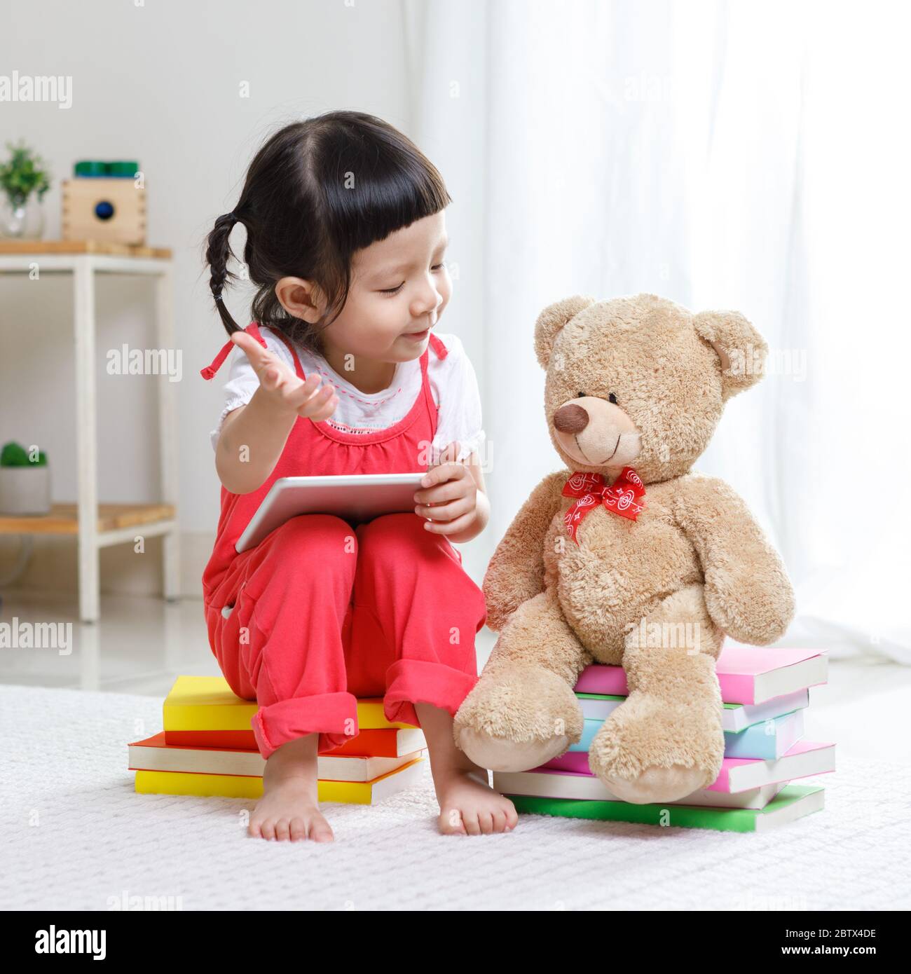 Adorable, riant petit enfant, petite fille d'âge préscolaire, portant un casque de sécurité jouant à l'intérieur de bâtiment maison avec des blocs colorés assis sur un sol Banque D'Images