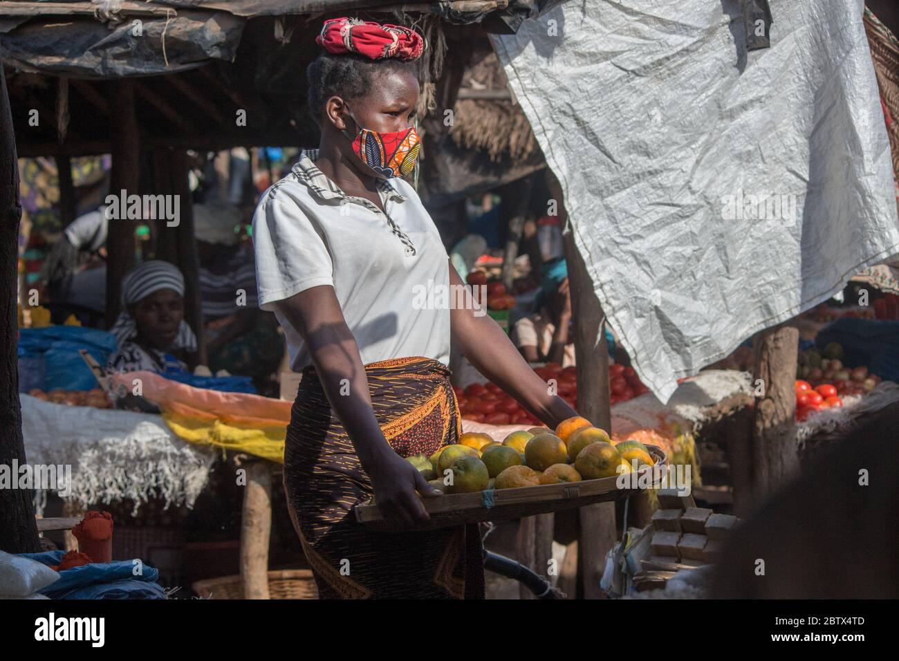 Fille de vendeur de rue informelle sur le marché, portant un masque de visage en tissu sarong africain pour la protection contre le virus corona Banque D'Images