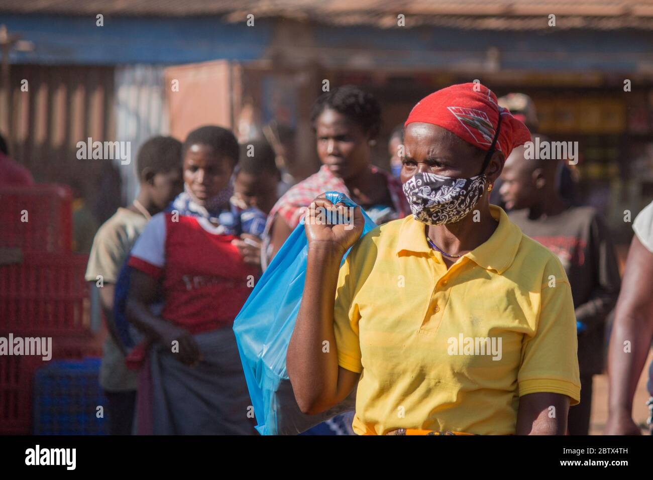 Femme sur le marché de la rue, portant un masque facial en tissu sarong africain pour la protection contre le virus corona Banque D'Images