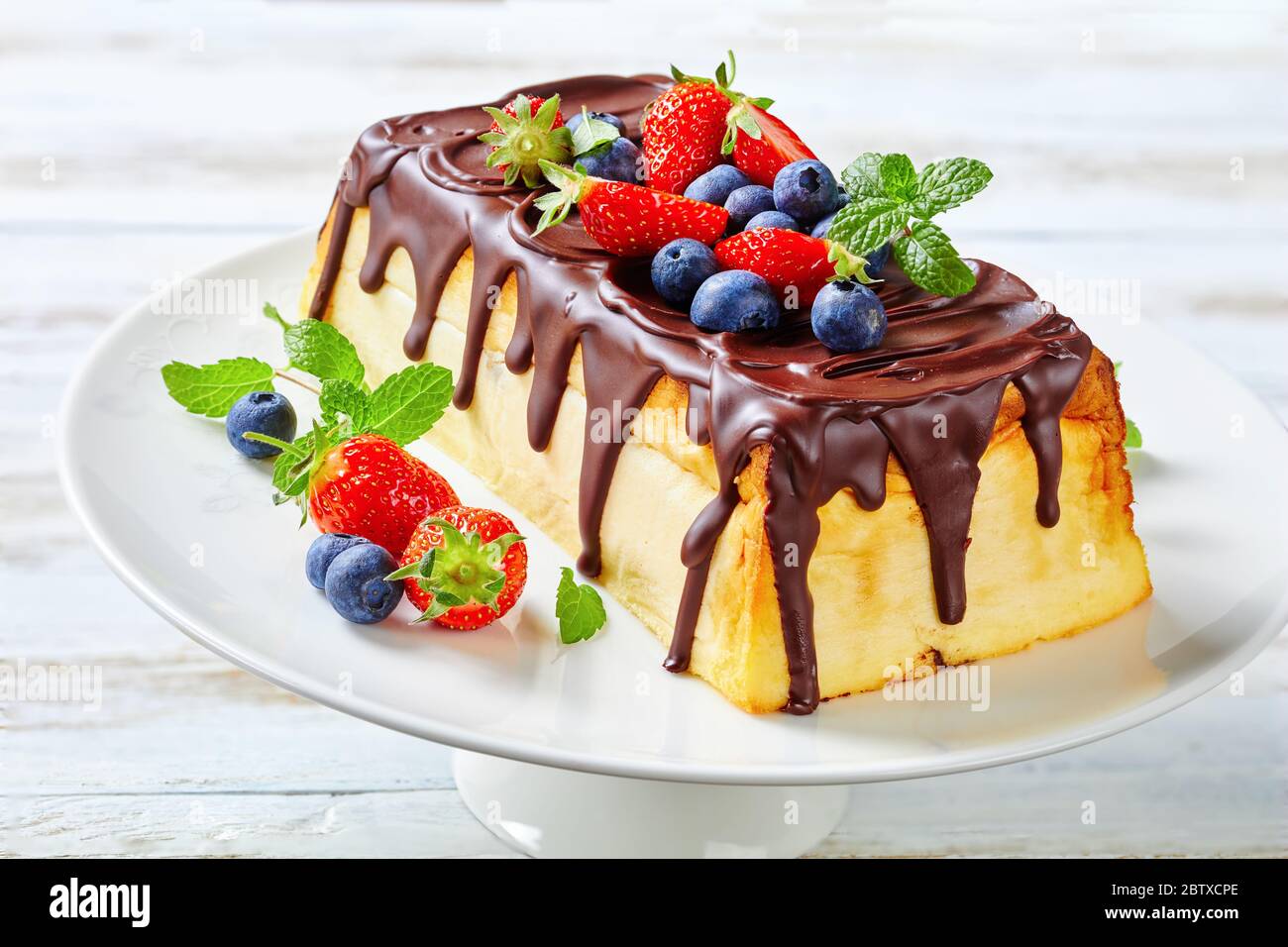 Dessert ukrainien : cheesecake lviv de fromage cottage, beurre, raisins secs nappés de chocolat servi avec des baies fraîches, des bleuets, des fraises, de la menthe Banque D'Images