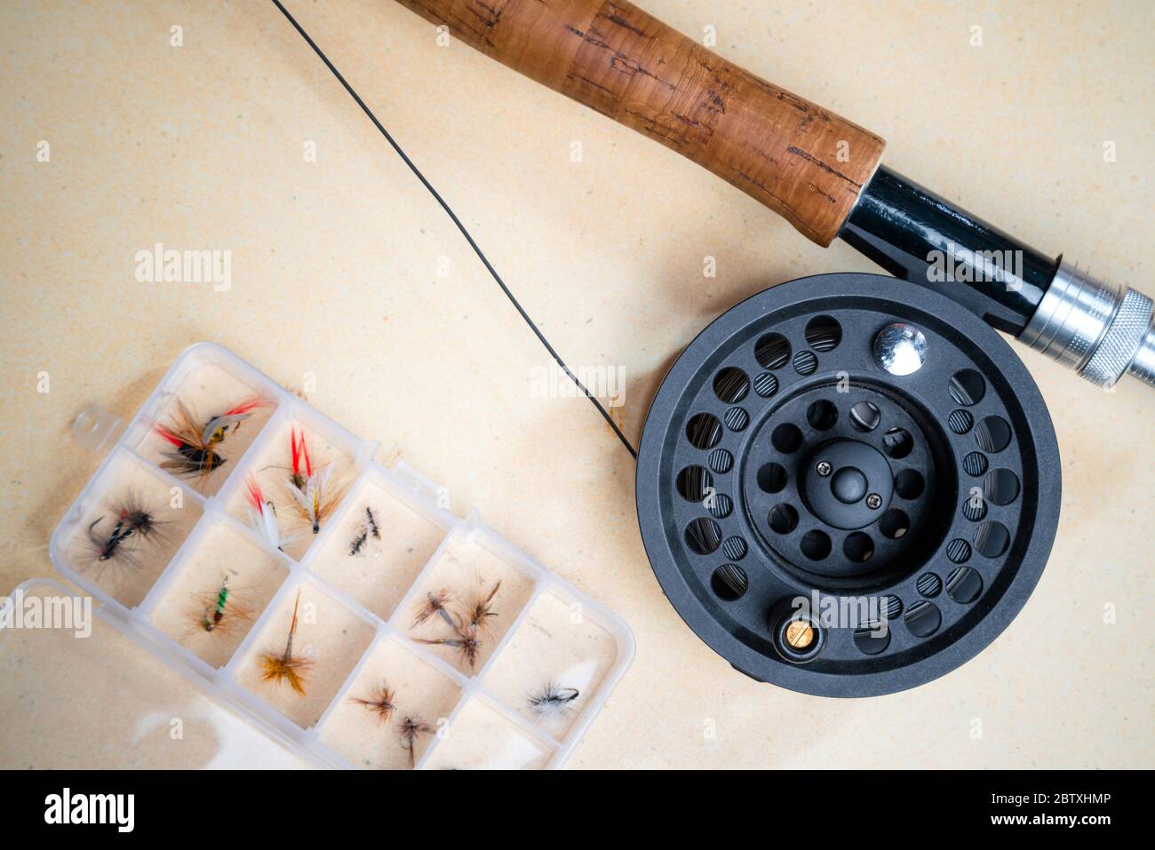 Gros plan de la canne à pêche à la mouche avec rabatteur à côté de la boîte avec mouches liées. L'équipement de pêche à la mouche est encore la vie. Personne Banque D'Images