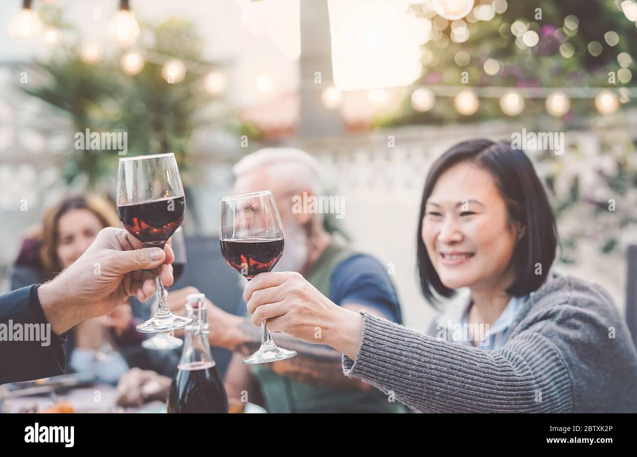 Une famille heureuse mangeant et buvant du vin rouge au dîner barbecue en plein air - des adultes et des jeunes dînant ensemble sur la terrasse Banque D'Images