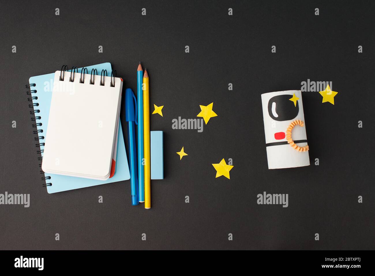 Formation créative. Concept de retour à l'école. L'astronaute de la fusée a coupé le tube de papier du rouleau de toilettes et les outils scolaires sur fond noir. Haut Banque D'Images