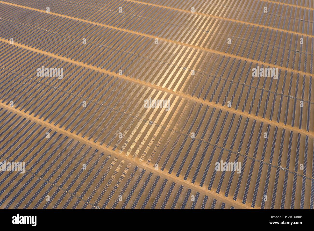 Vue aérienne d'une ferme de panneaux solaires photovoltaïques produisant une énergie renouvelable durable dans une centrale électrique désertique au coucher du soleil. Banque D'Images