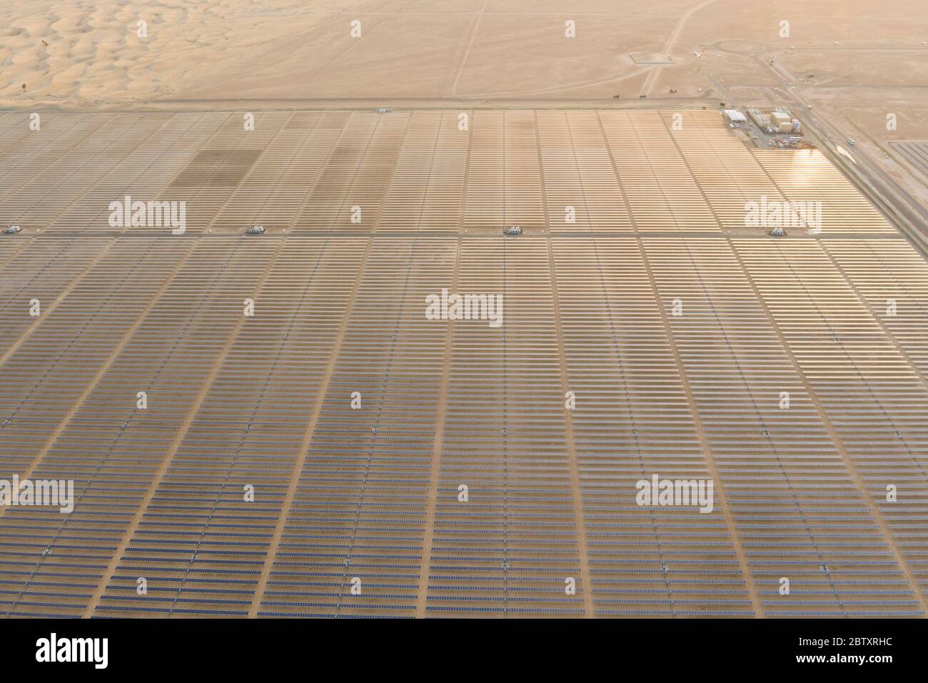 Vue aérienne d'un paysage avec une ferme de panneaux solaires photovoltaïques produisant une énergie renouvelable durable dans une centrale électrique du désert au coucher du soleil. Banque D'Images