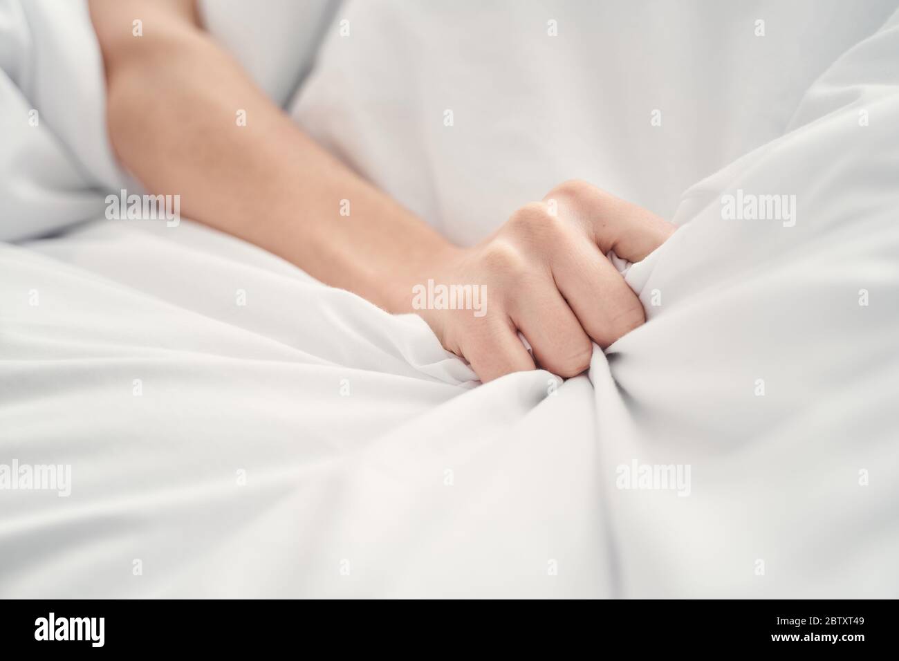 Femme couché à la main sur la couette froissés Banque D'Images