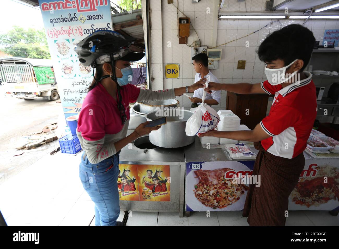 Yangon, Myanmar. 18 mai 2020. Le pilote de livraison féminin Khin min Shin (L) prend une commande dans un restaurant de Yangon, Myanmar, le 18 mai 2020. La restriction des repas assis dans les restaurants du Myanmar pendant la pandémie COVID-19 a laissé les services de livraison de nourriture monter sur les vagues depuis quelques mois. Khin min Shin est l'un des preneurs de risques qui veulent défier les choses dans la vie tout en faisant une vie. POUR ALLER AVEC 'Feature: Myanmar femme pilote de livraison reste fort dans la poursuite de la vie prospère dans le cadre de la pandémie de COVID-19' crédit: U Aung/Xinhua/Alay Live News Banque D'Images