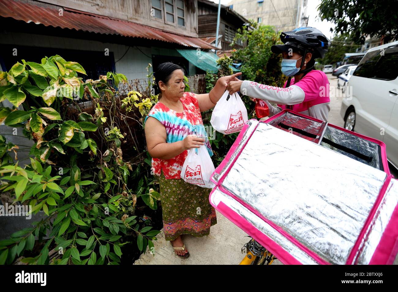 Yangon, Myanmar. 18 mai 2020. Le pilote de livraison féminin Khin min Shin livre de la nourriture à un client à Yangon, au Myanmar, le 18 mai 2020. La restriction des repas assis dans les restaurants du Myanmar pendant la pandémie COVID-19 a laissé les services de livraison de nourriture monter sur les vagues depuis quelques mois. Khin min Shin est l'un des preneurs de risques qui veulent défier les choses dans la vie tout en faisant une vie. POUR ALLER AVEC 'Feature: Myanmar femme pilote de livraison reste fort dans la poursuite de la vie prospère dans le cadre de la pandémie de COVID-19' crédit: U Aung/Xinhua/Alay Live News Banque D'Images