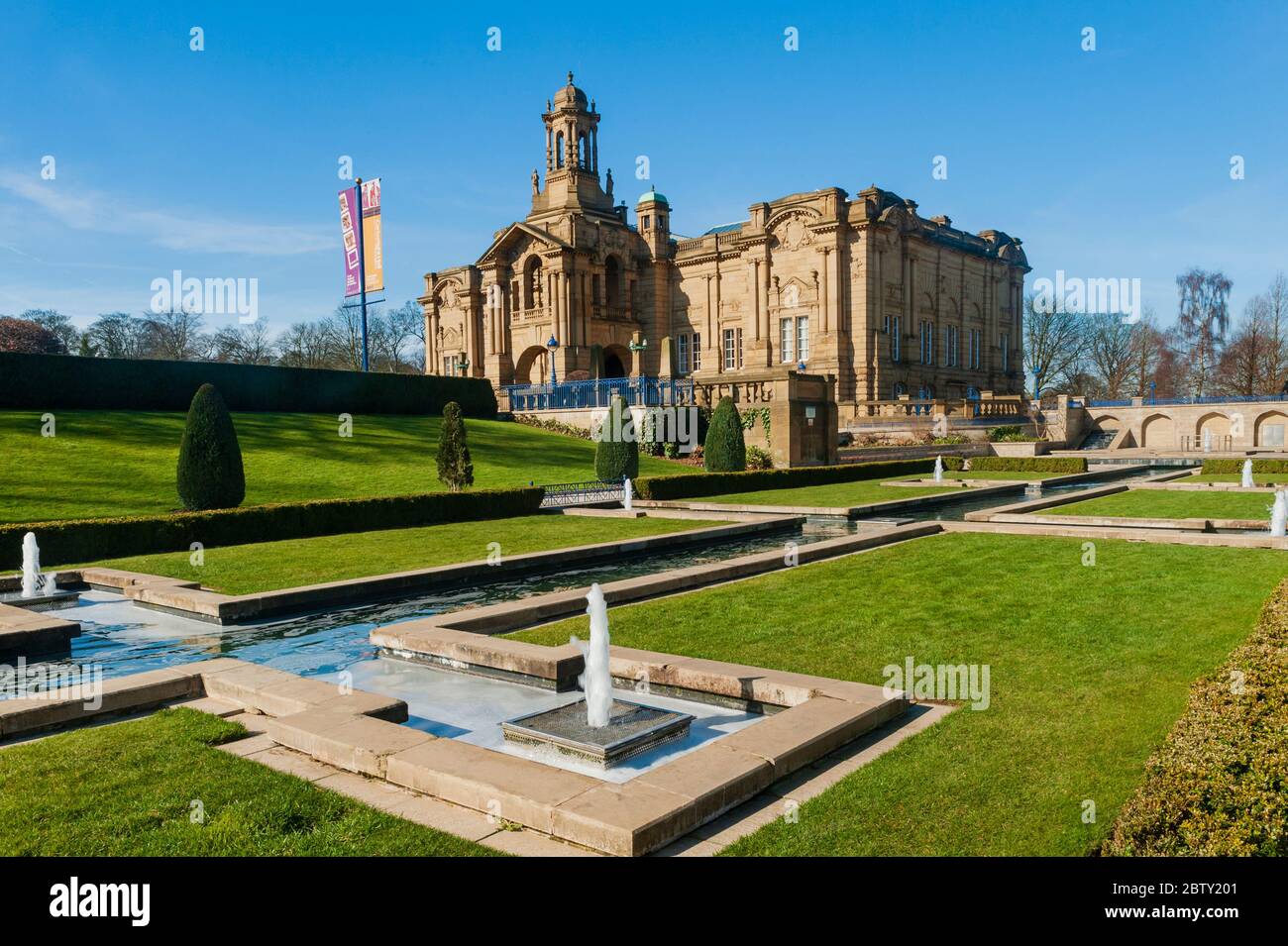 Extérieur de la galerie d'art civique de Cartwright Hall ensoleillée (grand bâtiment historique du musée) et fontaines de jardin aquatique Mughal - Lister Park, Bradford, Angleterre Banque D'Images