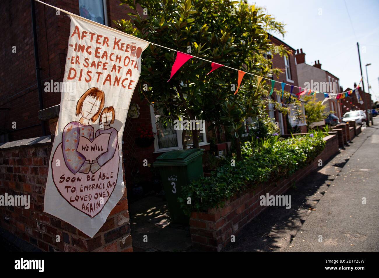 La rue Duncombe à Wollaston, où l'artiste Luke Perry a accroché des messages de soutien aux voisins et aux travailleurs clés, pour créer un couloir de couleur de 500 mètres à travers le village des West Midlands. M. Perry a demandé aux résidents et aux commerçants locaux de soumettre des dessins et des messages qu'il a ensuite peints et cousus à la main sur des banderoles avec l'aide de bénévoles. Banque D'Images