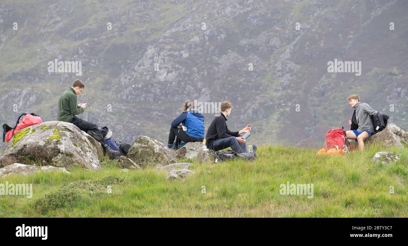 Jeunes de l'auberge de jeunesse sur les vacances d'été ensemble dans le nord du pays de Galles, prenant une pause bienvenue de leurs activités de randonnée en plein air, se détendre au pied des montagnes galloises, parc national de Snowdonia, Royaume-Uni. Banque D'Images