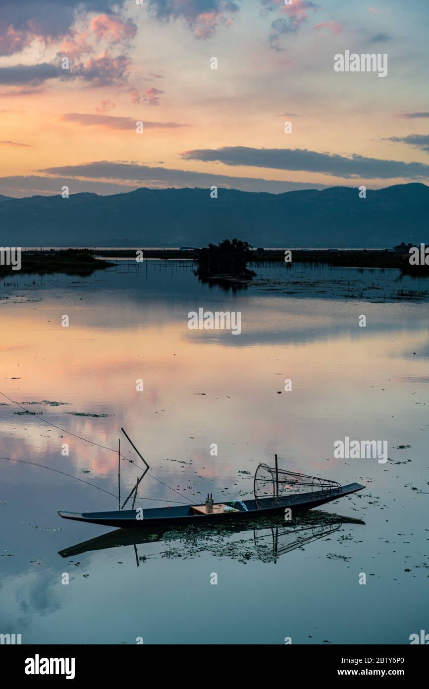 Nuages et bateau à rames traditionnel se reflétant dans l'eau au coucher du soleil, lac Inle, état Shan, Myanmar (Birmanie), Asie Banque D'Images