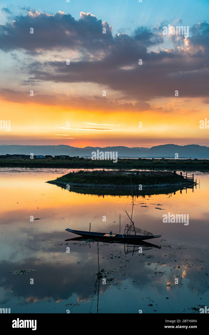 Nuages et bateau à rames traditionnel se reflétant dans l'eau au coucher du soleil, lac Inle, état Shan, Myanmar (Birmanie), Asie Banque D'Images
