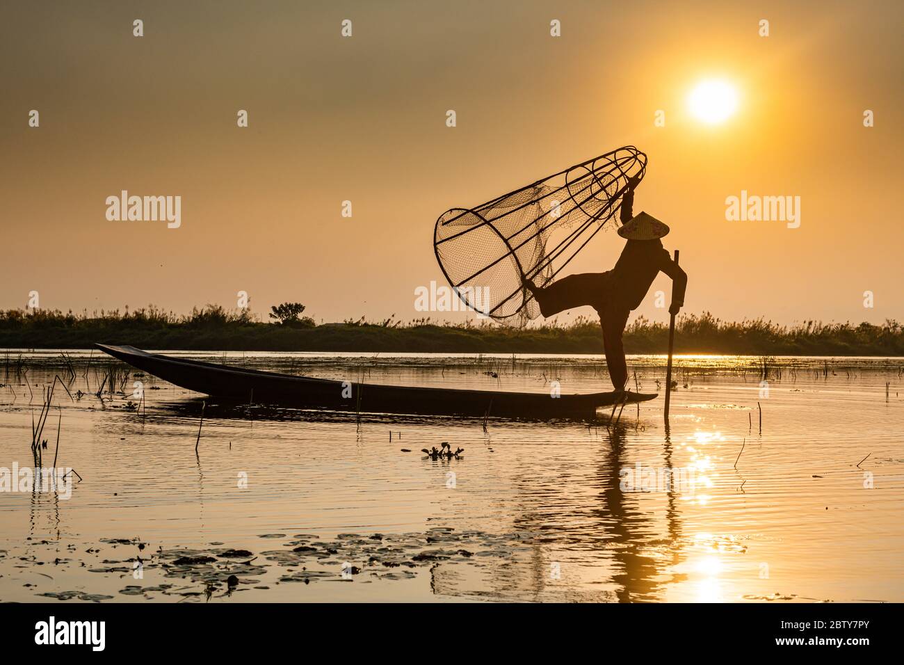Pêcheur au lac Inle avec filet conique traditionnel Intha au coucher du soleil, filet de pêche, rames de jambe, peuple Intha, lac Inle, État Shan, Myanmar (Burm Banque D'Images