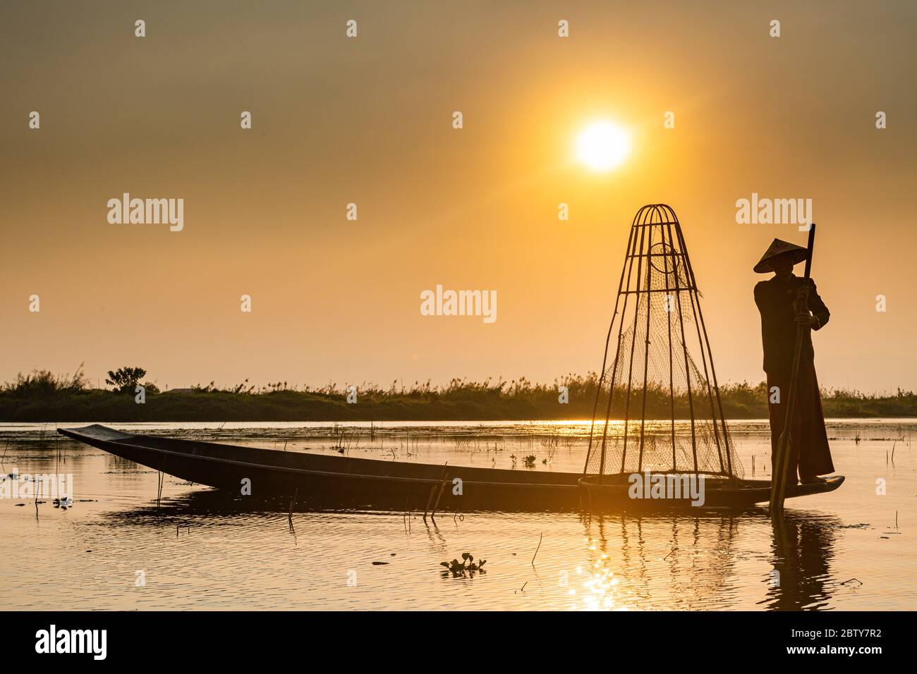 Pêcheur au lac Inle avec filet conique traditionnel Intha au coucher du soleil, filet de pêche, rames de jambe, peuple Intha, lac Inle, État Shan, Myanmar (Burm Banque D'Images