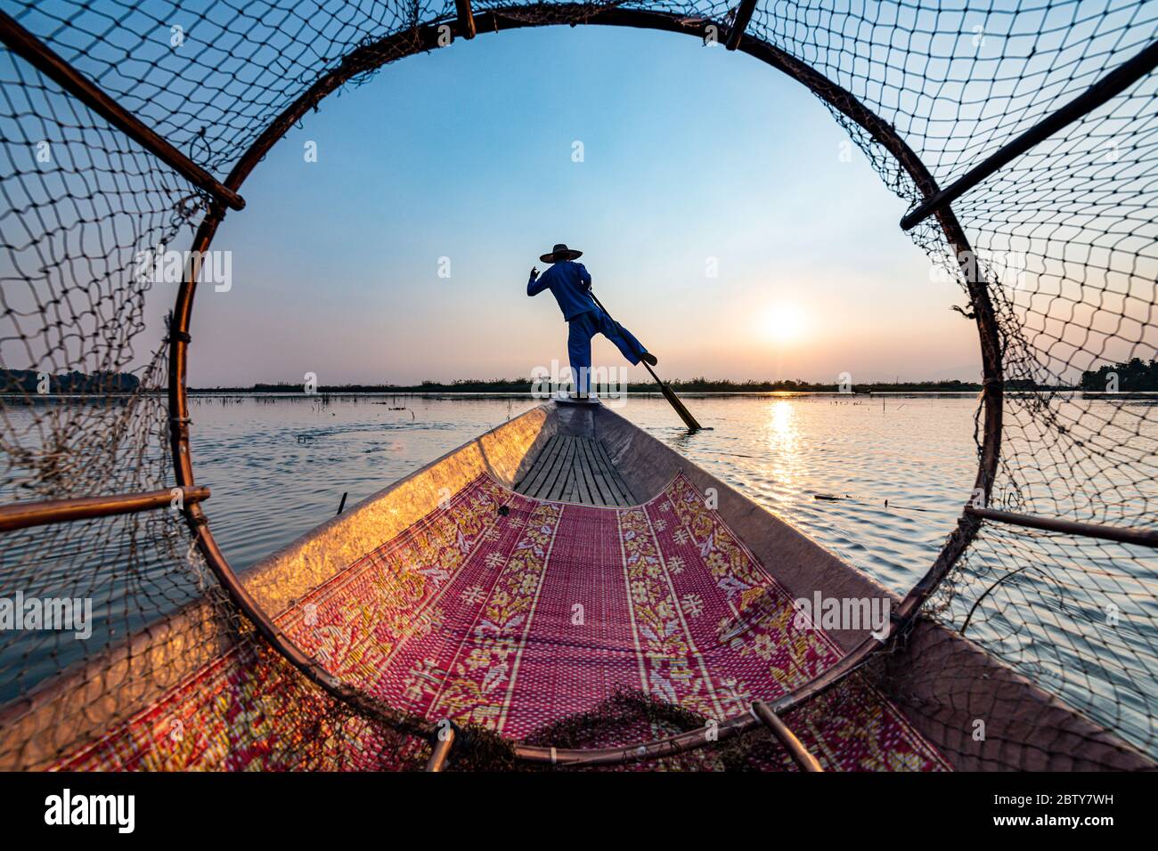 Pêcheur au lac Inle avec filet conique traditionnel Intha au coucher du soleil, filet de pêche, rames de jambe, peuple Intha, lac Inle, État Shan, Myanmar (Burm Banque D'Images