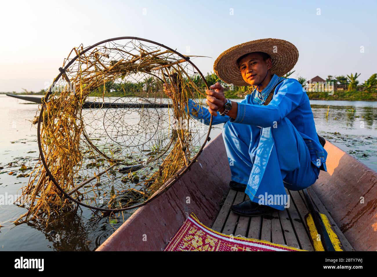 Pêcheur au lac Inle avec filet conique traditionnel Intha au coucher du soleil, filet de pêche, rames de jambe, peuple Intha, lac Inle, État Shan, Myanmar (Burm Banque D'Images