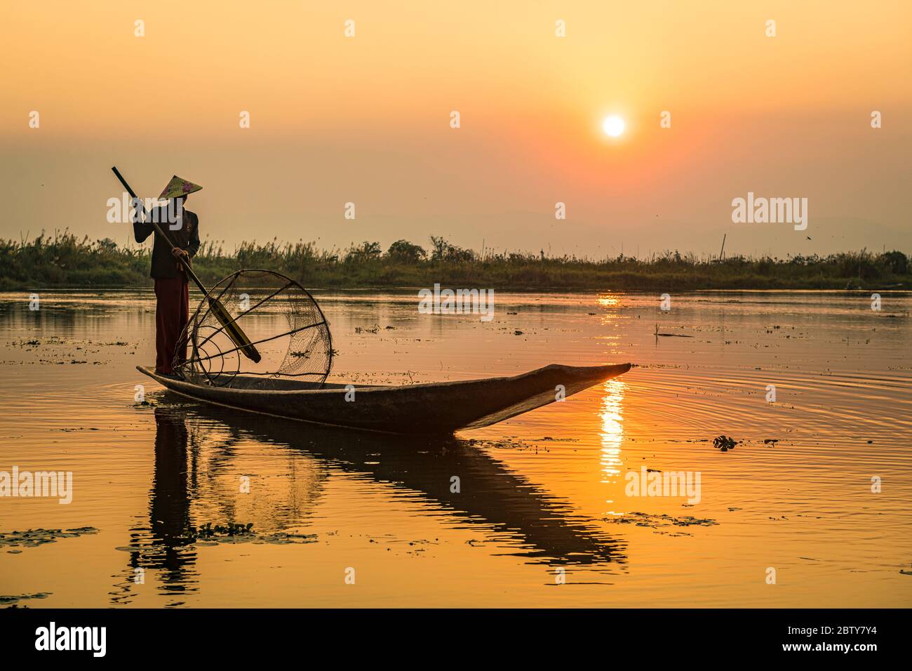 Pêcheur au lac Inle avec filet conique traditionnel Intha au coucher du soleil, filet de pêche, rames de jambe, peuple Intha, lac Inle, État Shan, Myanmar (Burm Banque D'Images