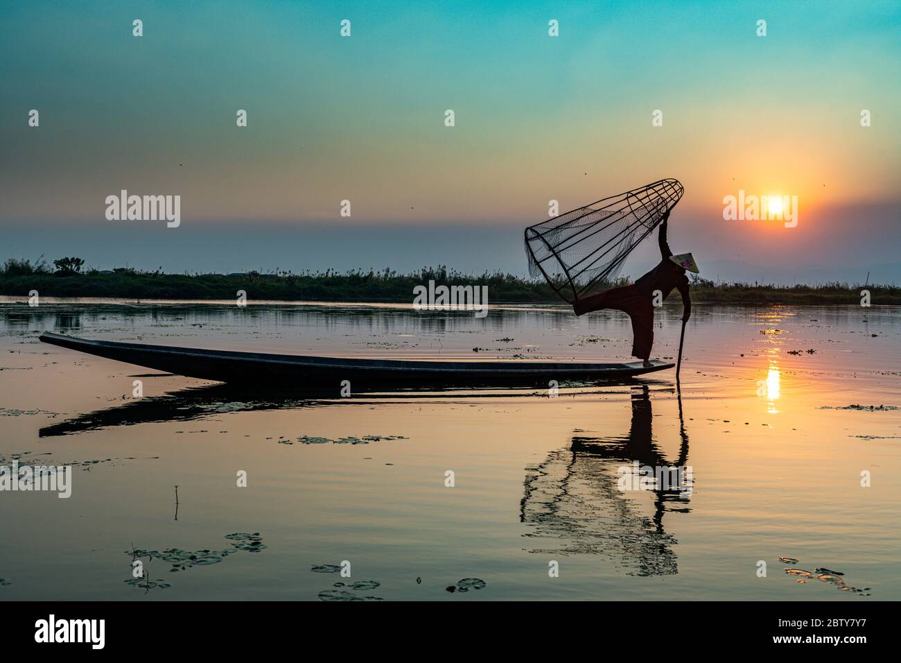 Pêcheur au lac Inle avec filet conique traditionnel Intha au coucher du soleil, filet de pêche, rames de jambe, peuple Intha, lac Inle, État Shan, Myanmar (Burm Banque D'Images