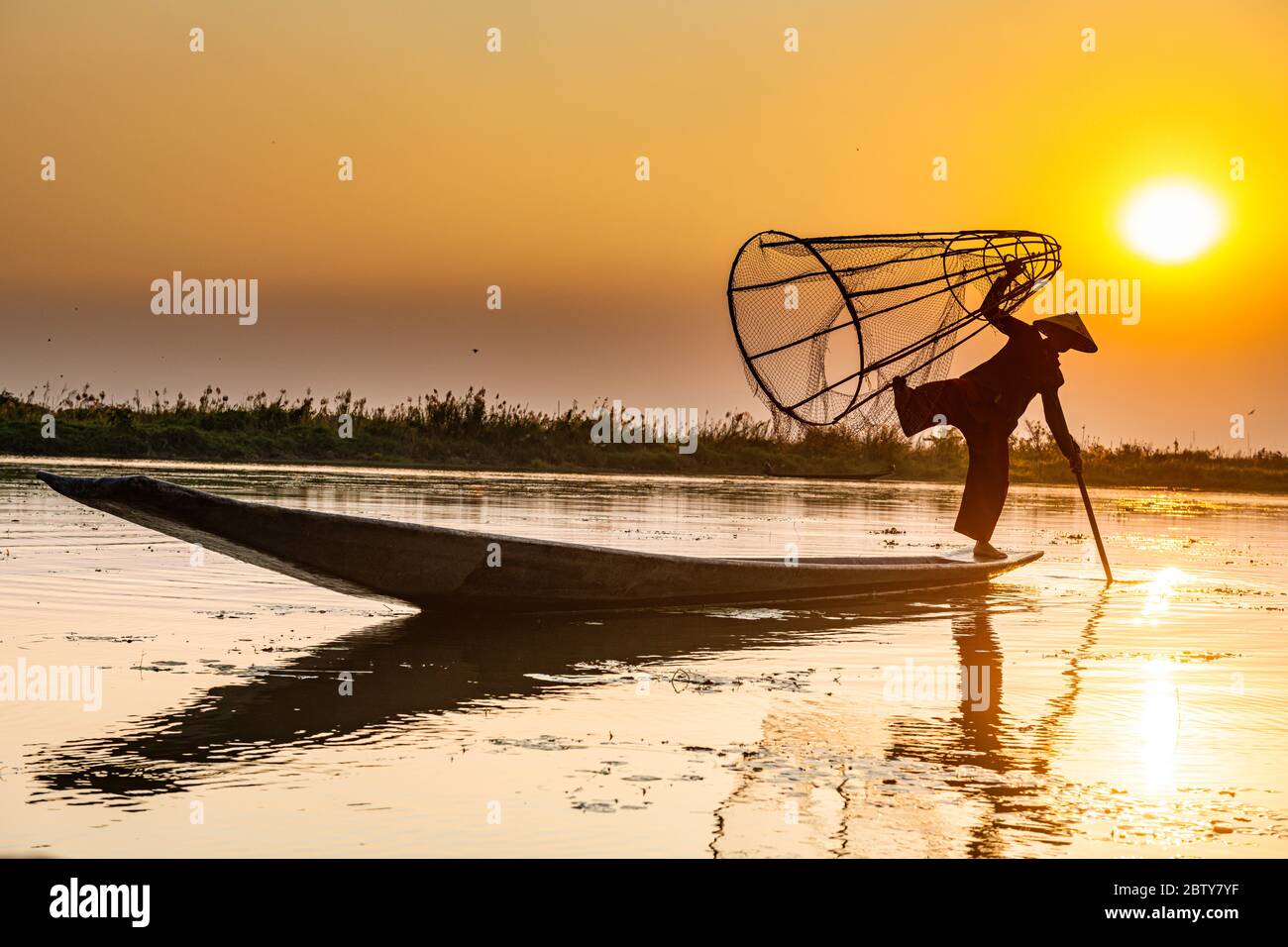 Pêcheur au lac Inle avec filet conique traditionnel Intha au coucher du soleil, filet de pêche, rames de jambe, peuple Intha, lac Inle, État Shan, Myanmar (Burm Banque D'Images