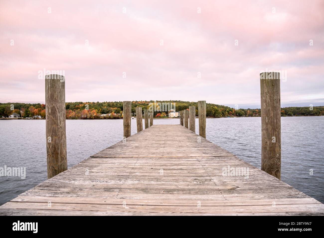 Jetée en bois déserte sur un lac au crépuscule. Magnifique feuillage d'automne visible de l'autre côté du lac. Concept de tranquillité. Banque D'Images