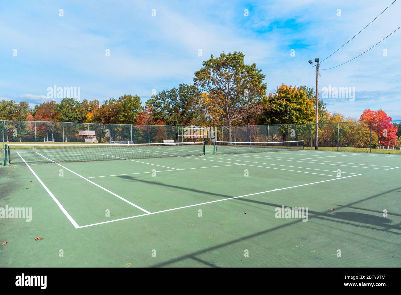 Courts de tennis vides avec arbres colorés en arrière-plan dans un parc public, le matin ensoleillé de l'automne Banque D'Images