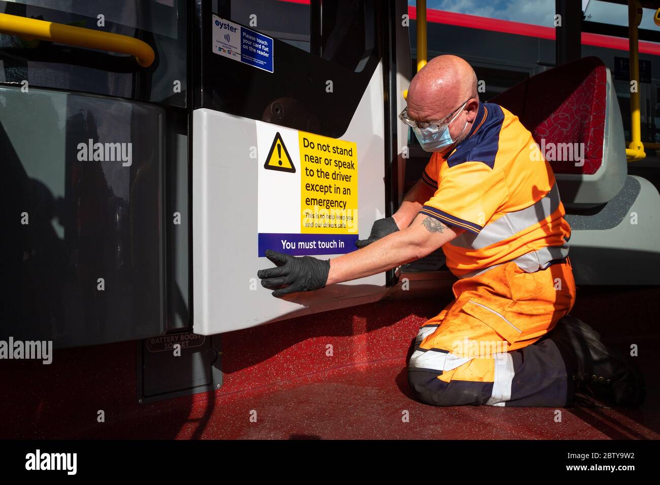 Le personnel de l'autobus pose des autocollants sur un autobus dans le garage de l'autobus de Twickenham pour rappeler aux clients que les tarifs sont en vigueur sur l'itinéraire, pendant le pandemi COVID-19 Banque D'Images