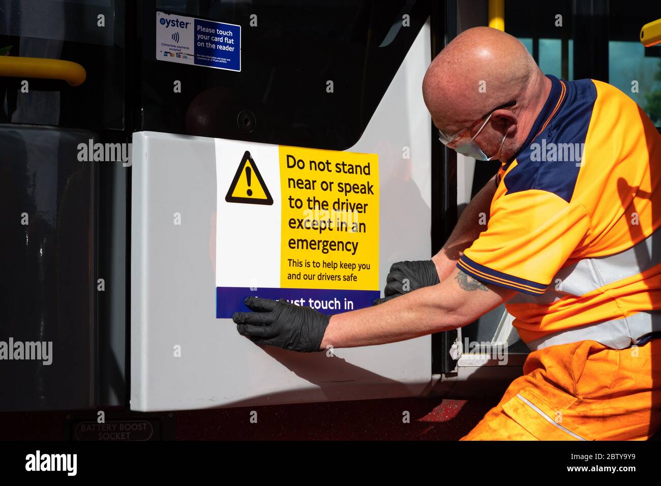 Le personnel de l'autobus pose des autocollants sur un autobus dans le garage de l'autobus de Twickenham pour rappeler aux clients que les tarifs sont en vigueur sur l'itinéraire, pendant le pandemi COVID-19 Banque D'Images