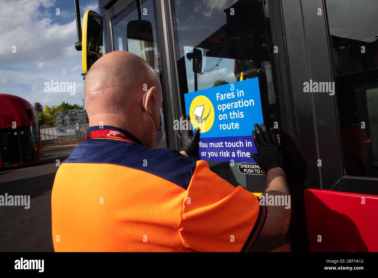 Le personnel de l'autobus pose des autocollants sur un autobus dans le garage de l'autobus de Twickenham pour rappeler aux clients que les tarifs sont en vigueur sur l'itinéraire, pendant le pandemi COVID-19 Banque D'Images