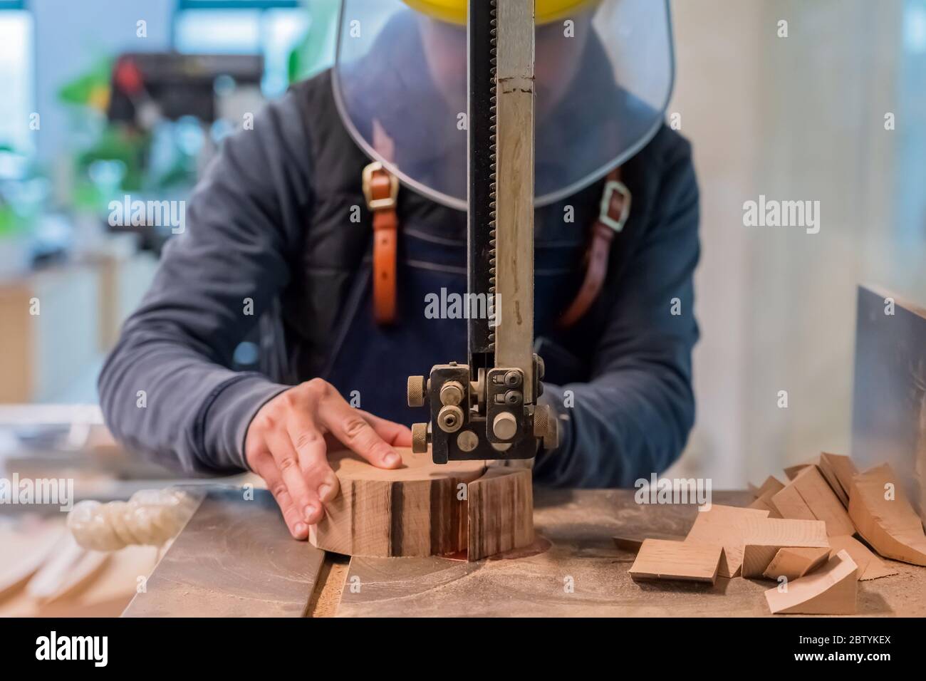 Carpenter coupe la pièce en bois par l'équipement sur le support. La main de l'homme fait un rond détail de la bûche. Le raccord utilise une scie électrique à métaux Banque D'Images