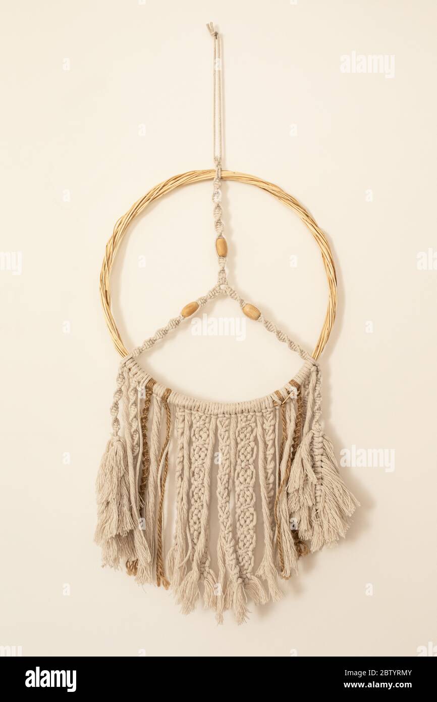 Maison bricolage décoration coton macrame pendentif mural suspendu sur un mur beige. Décoration intérieure confortable et romantique de style boho. Composition verticale Banque D'Images