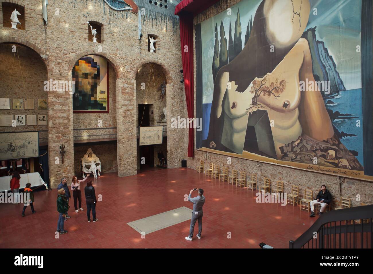 Les visiteurs séjournent à côté de la tombe non marquée du peintre surréaliste espagnol Salvador Dalí dans la salle principale du théâtre et musée Salvador Dalí à Figueres, Catalogne, Espagne. L'immense toile de fond conçue par Salvador Dalí pour le ballet Labyrinth (1941) est vue dans le fond à droite. La peinture de Salvador Dalí intitulée 'Lincoln in Dalivision' est vue à gauche. Banque D'Images