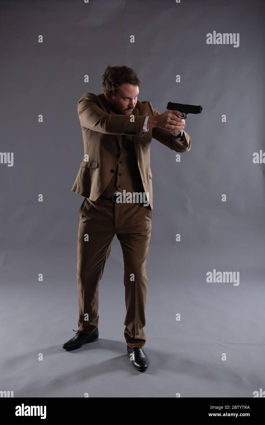 Image isolée d'un flic sous couverture avec un pistolet sur fond Uni, idéale pour le design de couverture d'ebook et les vestes de livre Banque D'Images