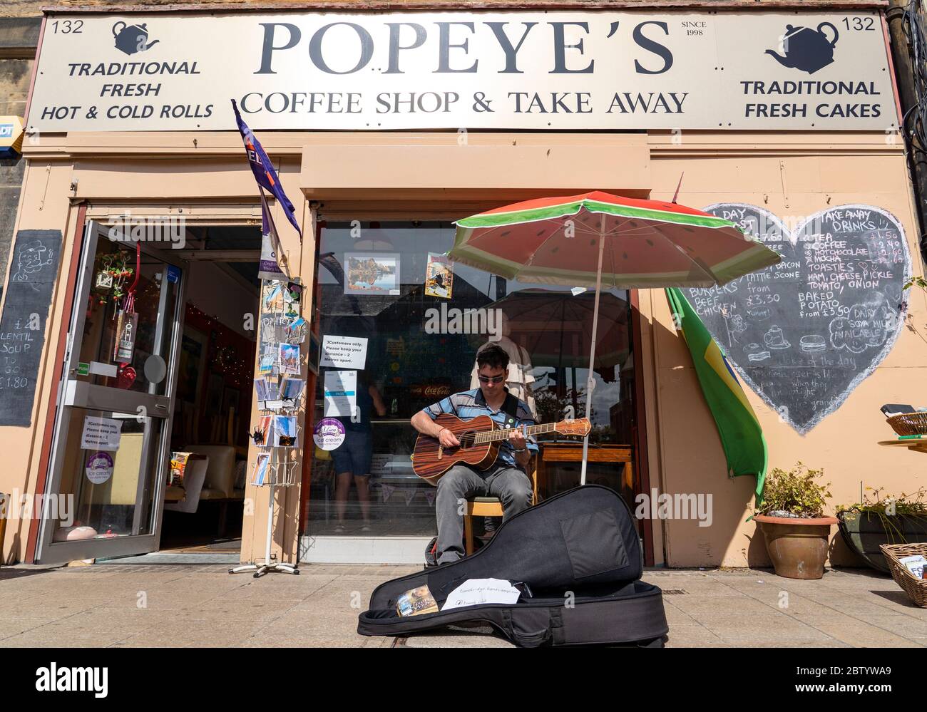 Portobello, Écosse, Royaume-Uni. 28 mai 2020. Le temps ensoleillé et chaud avec des températures atteignant 24°C a amené de nombreuses personnes à la plage et à la promenade de Portobello, Édimbourg. Le public semble avoir le sentiment que le verrouillage est détendu sont profiter du bon temps pour bronzer et profiter des nombreux cafés qui offrent maintenant des collations à emporter. Photo. Busker à l'extérieur du café ouvert sur Portobello High Street. Iain Masterton/Alay Live News Banque D'Images