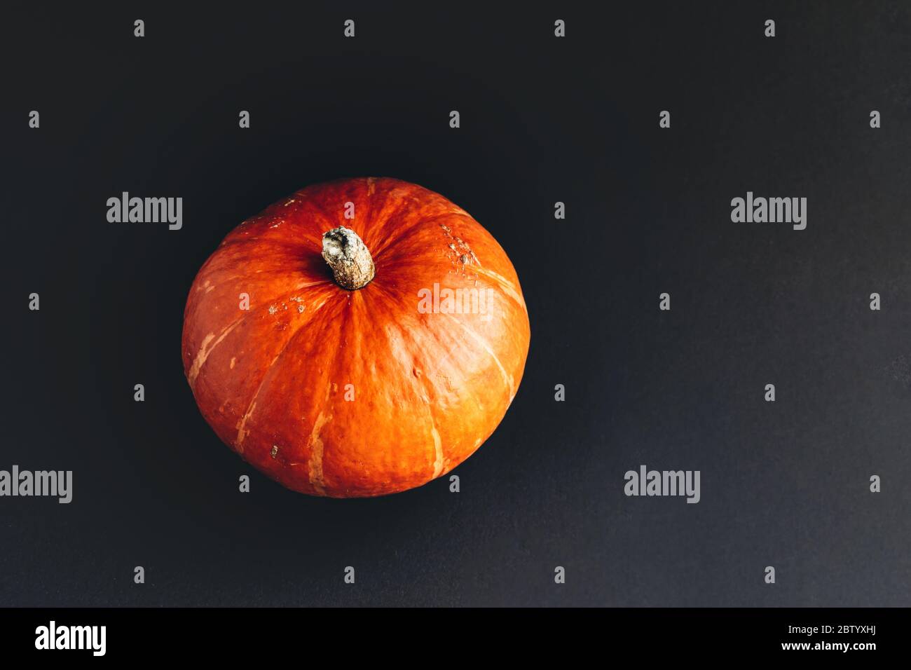 Citrouille orange avec ombre dure sur fond noir. Concept Halloween. Banque D'Images