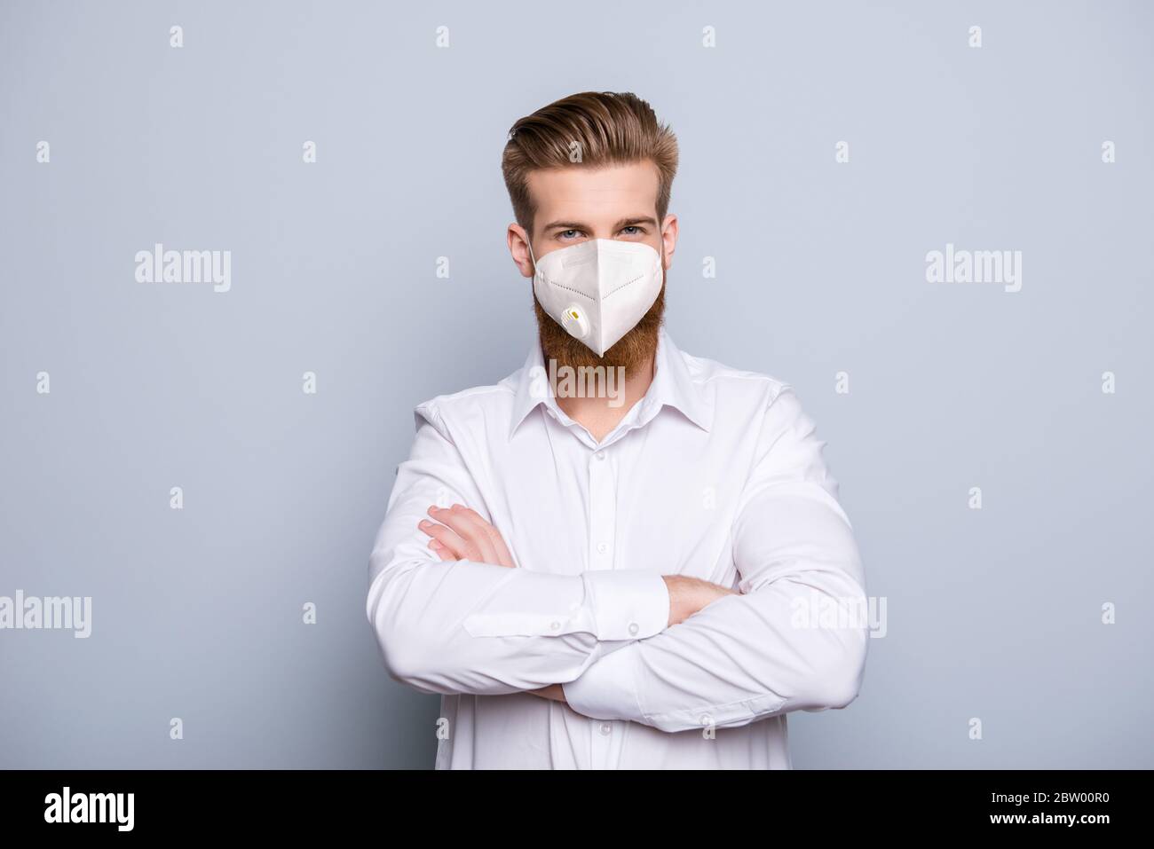 Portrait de son beau virile beau contenu masculin sain funky gars portant un manteau blanc médical réutilisable masque bras pliés isolés sur gris Banque D'Images