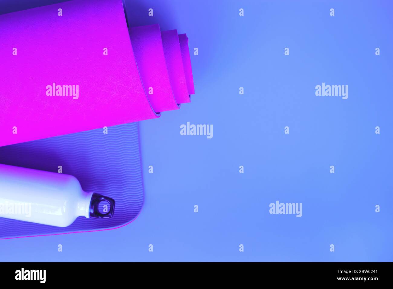 Tapis de yoga violet vif et bouteille d'eau. Banque D'Images